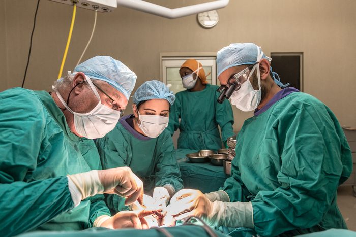 Robyn Midgley working alongside surgeons in theatre during hand surgery